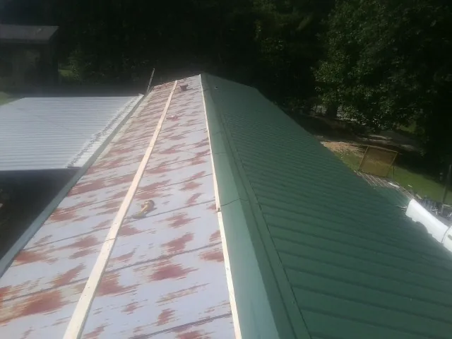 Old rusted panels beside newly installed green metal roofing — Wind Damage Roof Repair by Roofing Brothers in Farmingdale