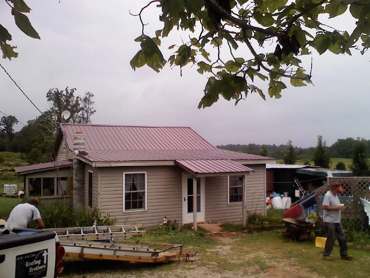 Crew finishing a mauve metal roof on a small farmhouse in Farmingdale