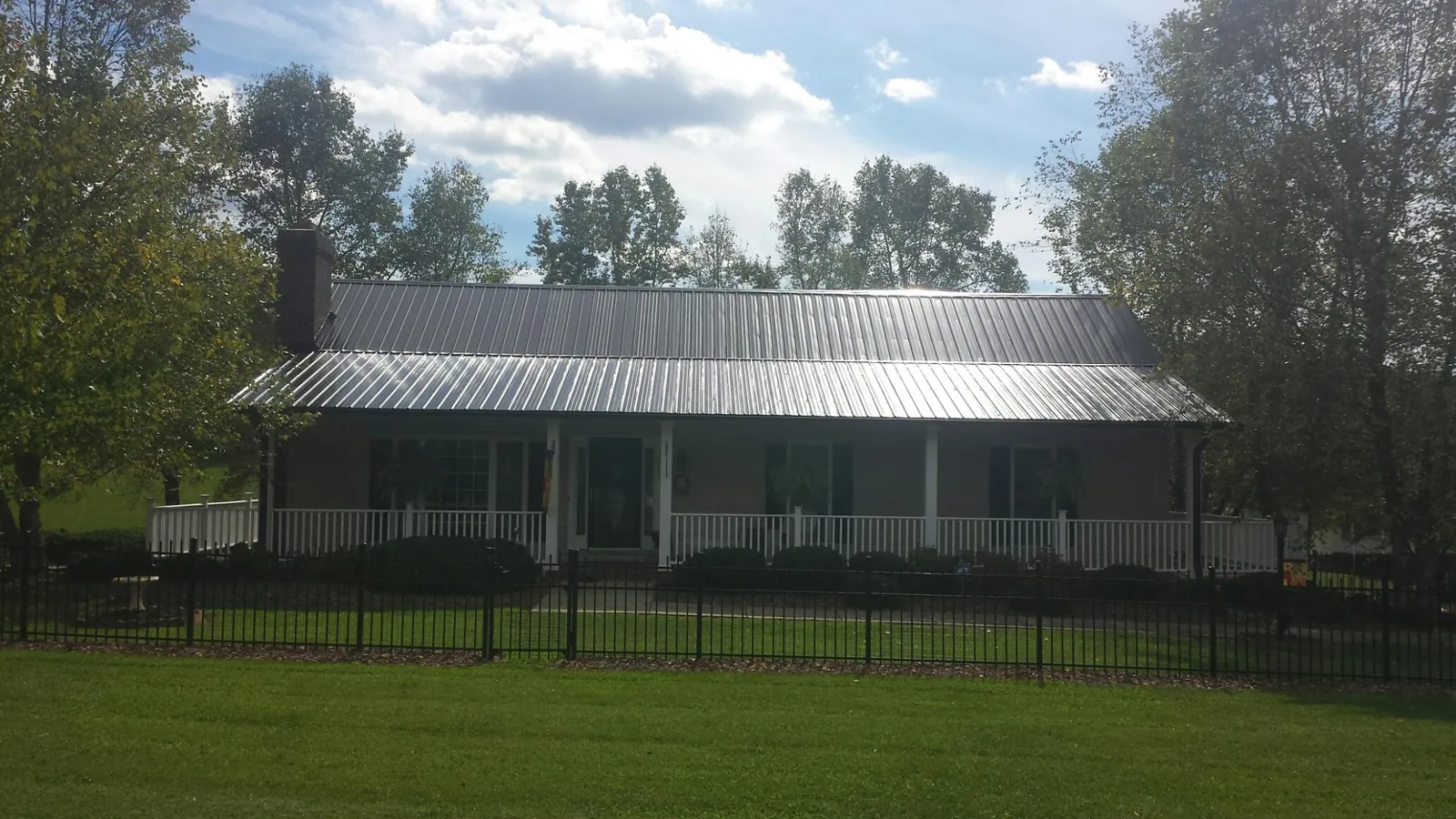 Gray metal roof on a brick ranch with a full width front porch — Gutter Guard Installation work by our crew in Farmingdale