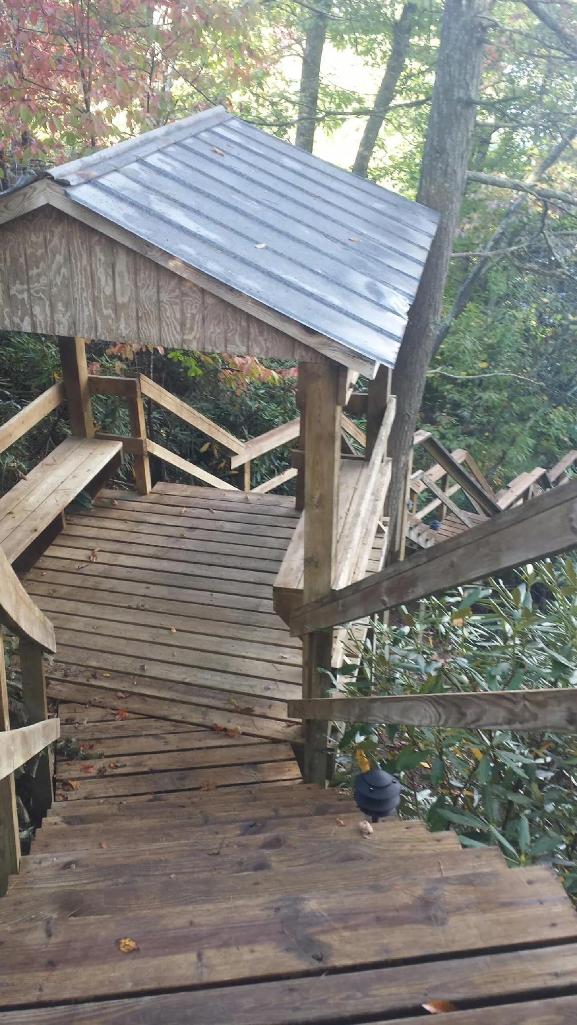 Metal roofed shelter over wooden steps on a wooded walkway — Skylight Repair & Installation work by our crew in Farmingdale